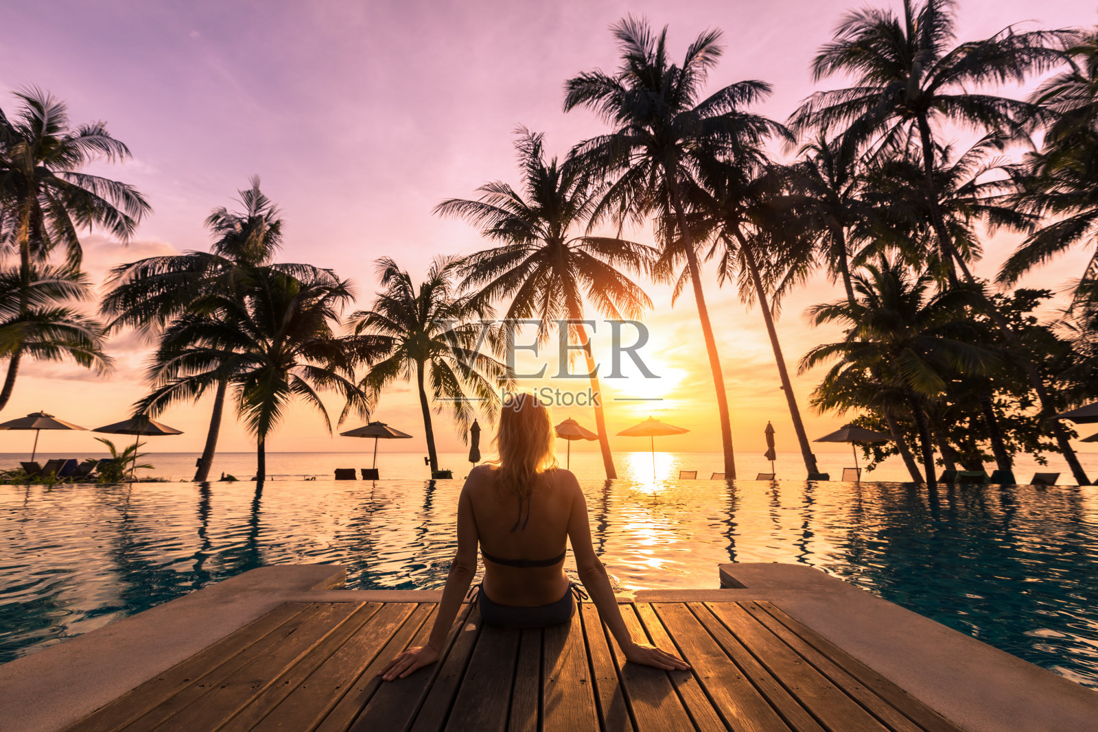 女人放松在豪华的海滨酒店度假村的游泳池照片摄影图片