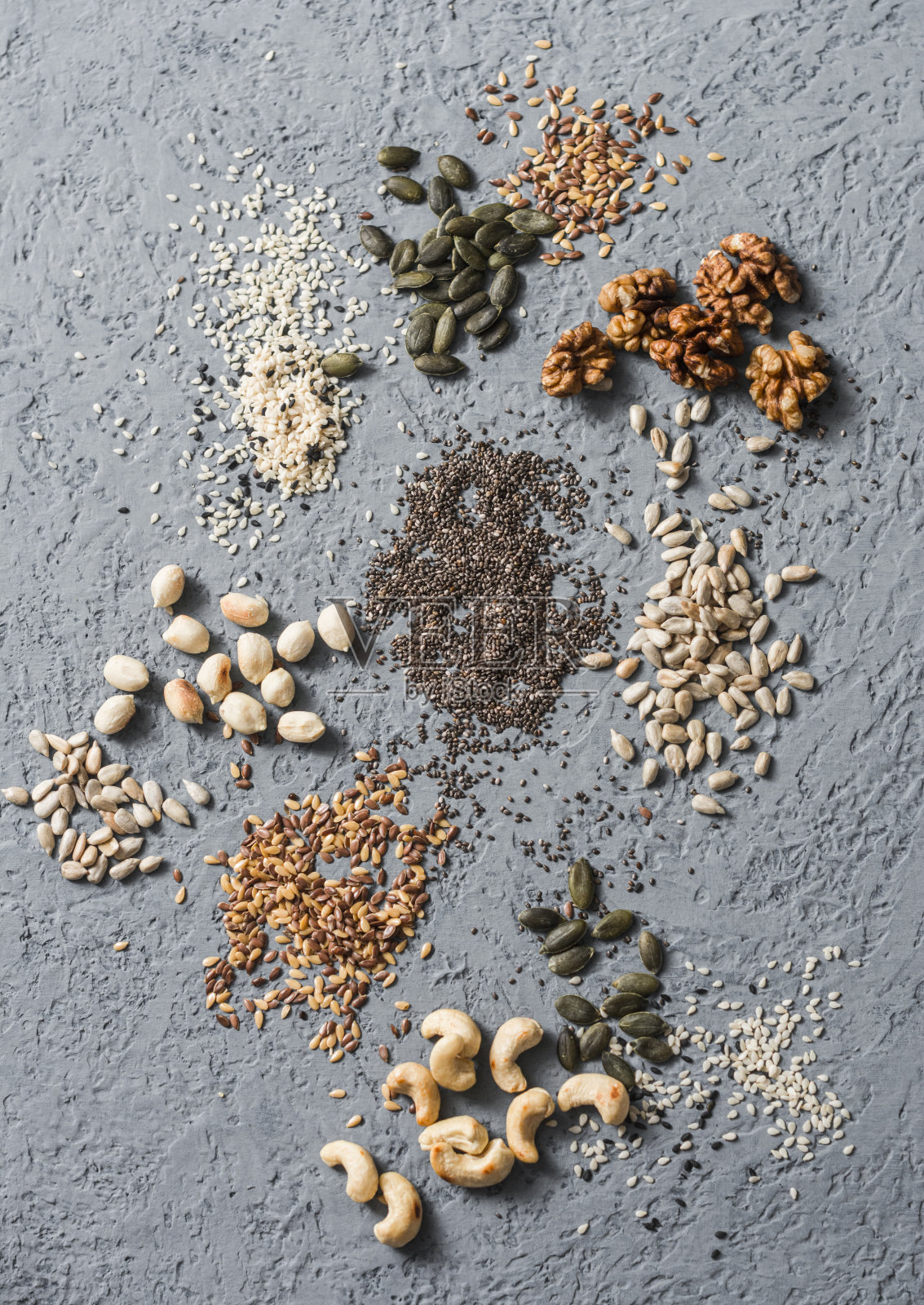 超级食品配料。在灰色背景上分类种子和坚果，俯视图。亚麻籽，芝麻籽，核桃，葵花籽，腰果，南瓜籽，花生。健康食品的概念照片摄影图片
