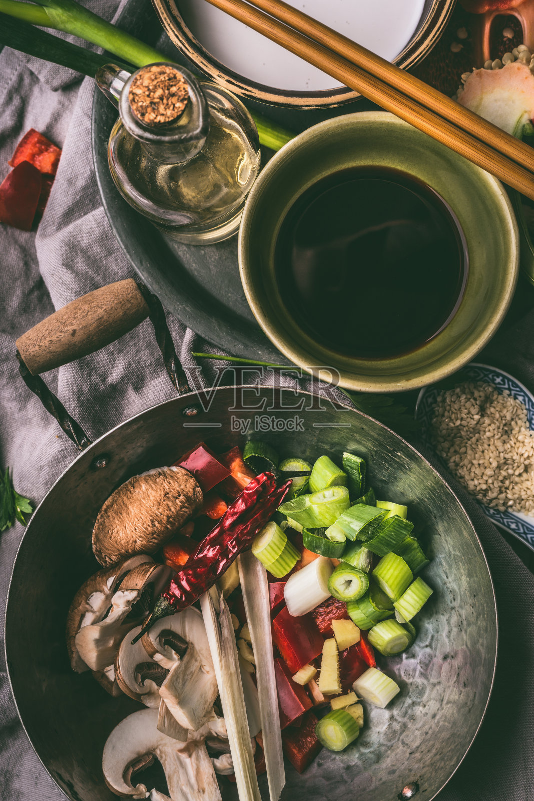 用筷子、酱油和芝麻油将炒锅放入切碎的蔬菜和香料。照片摄影图片