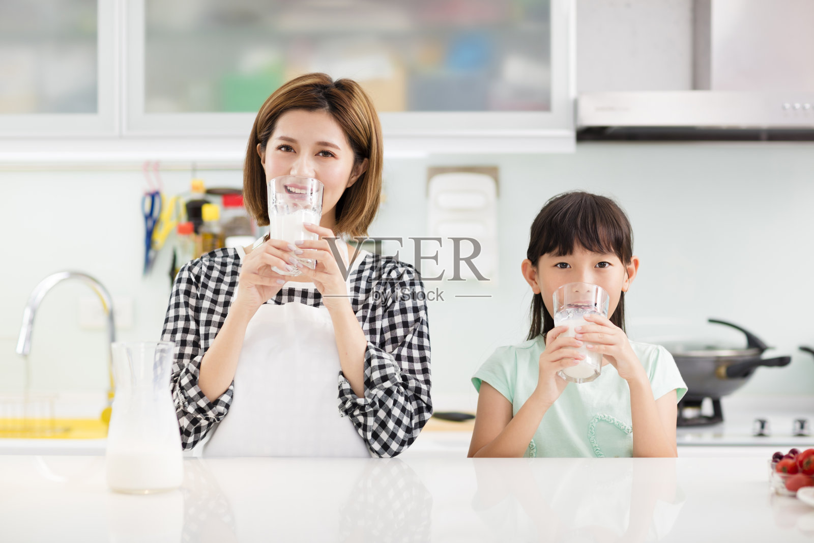 快乐的母亲和孩子在厨房喝牛奶照片摄影图片