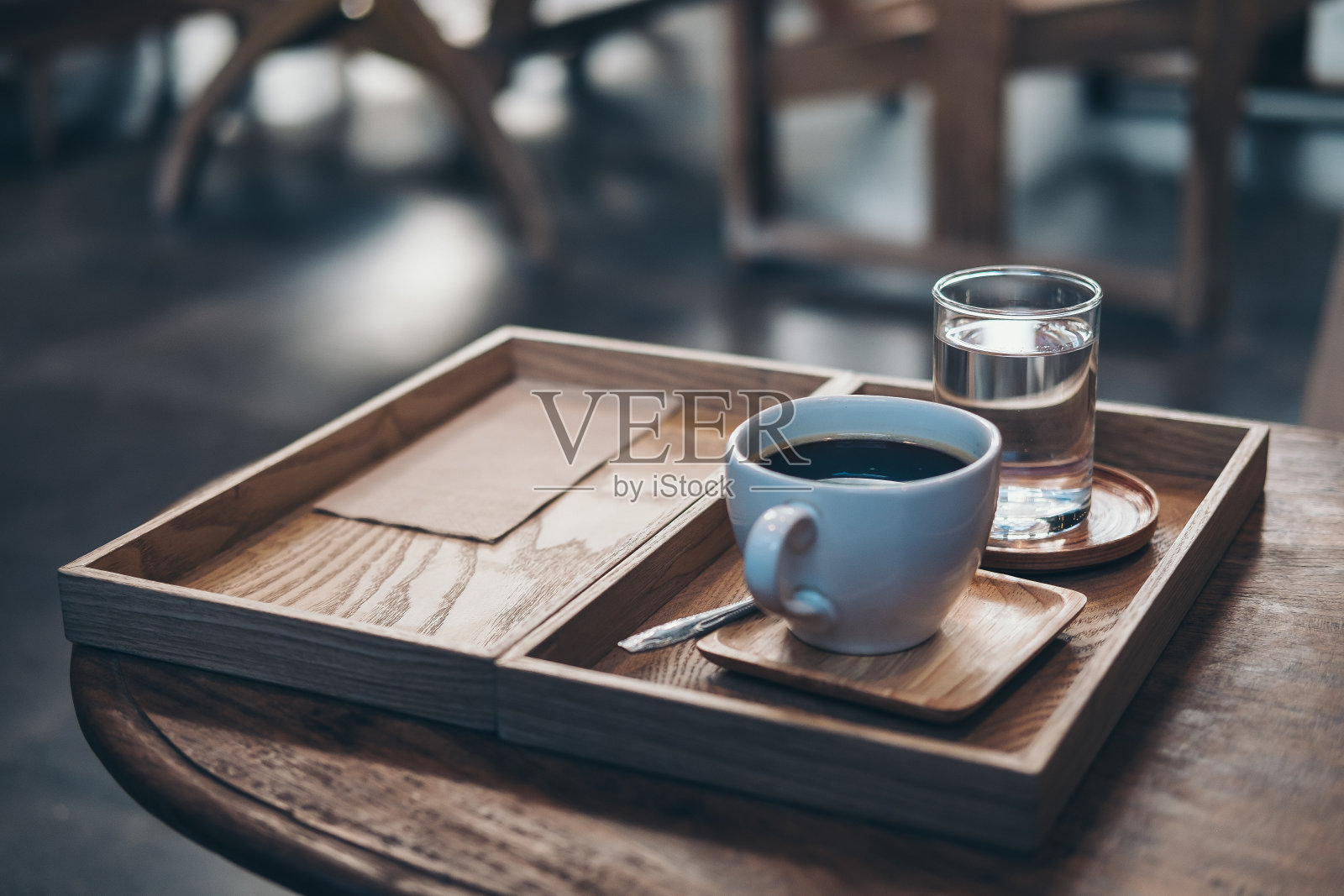 特写的一杯热咖啡和一杯水在咖啡馆的桌子上的古董木托盘照片摄影图片