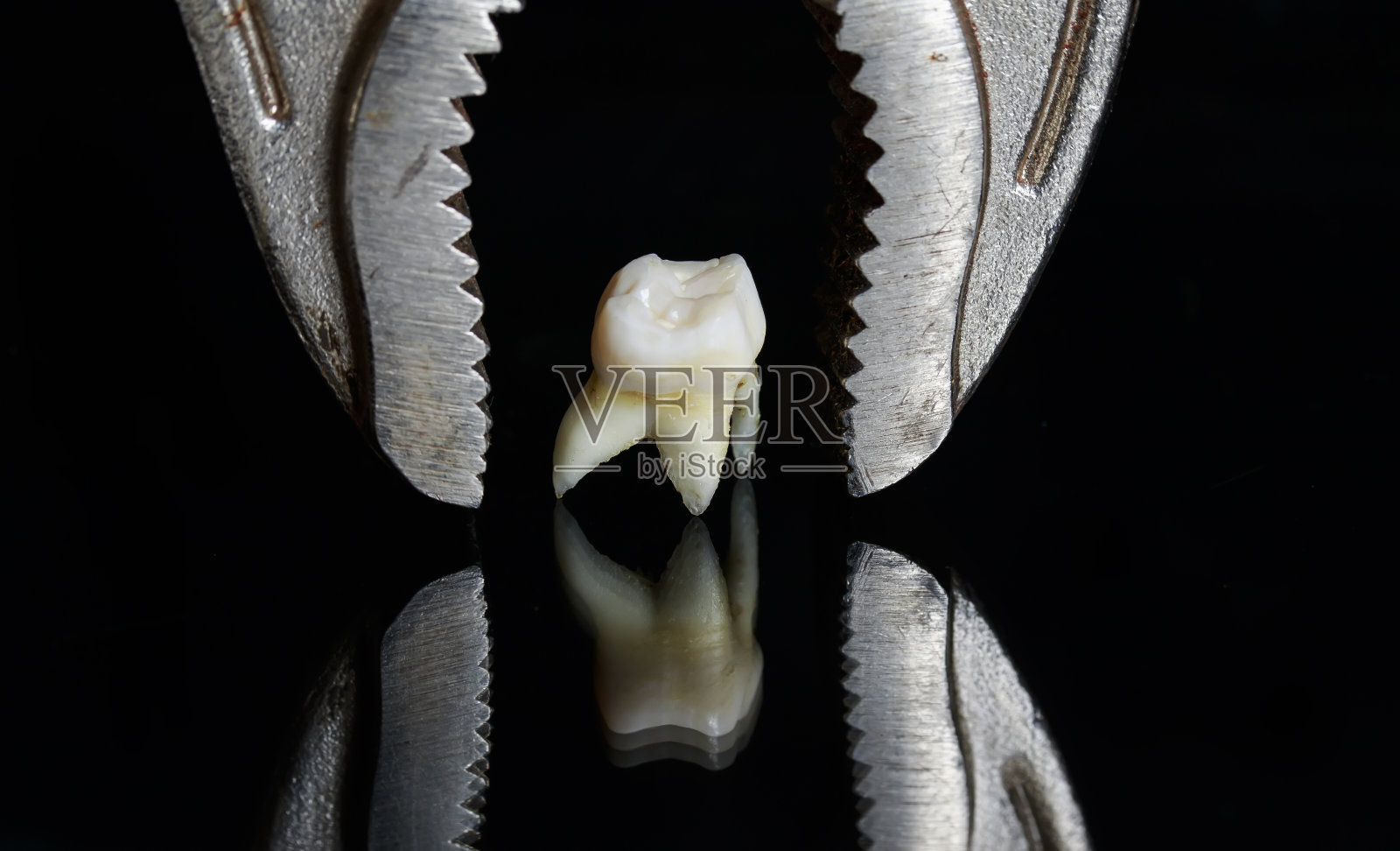 可怕的金属钳子在一个坏的蛀牙拔出，站在一个黑色孤立的背景照片摄影图片