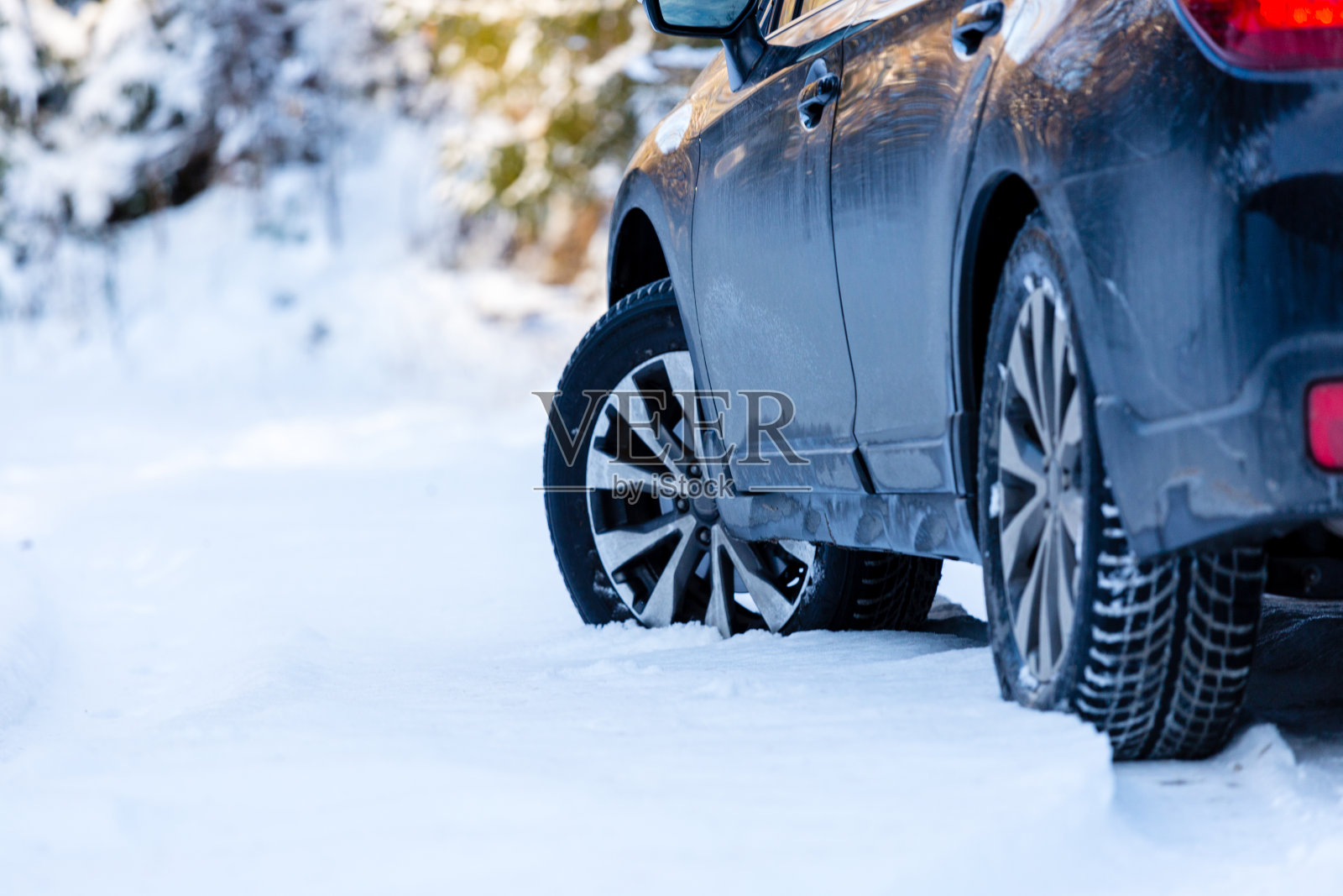 冬用轮胎。雪地森林道路上的黑色SUV汽车后视图。冬天的条件。照片摄影图片