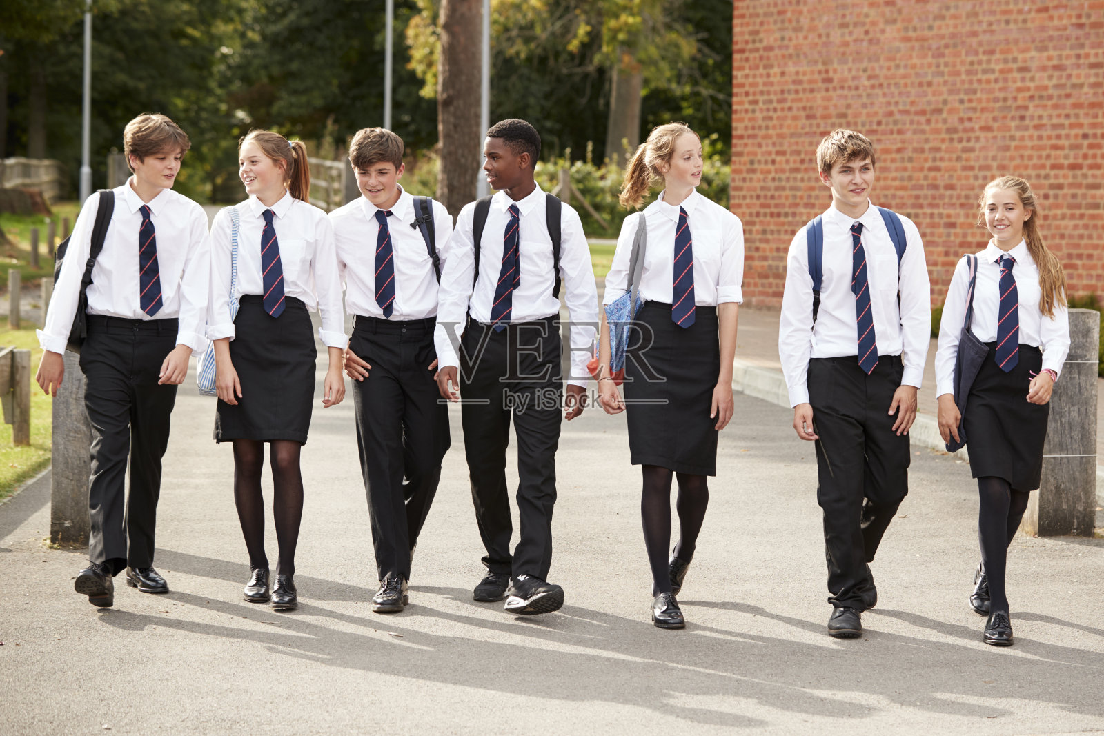 一群十几岁的学生在学校大楼外穿制服照片摄影图片
