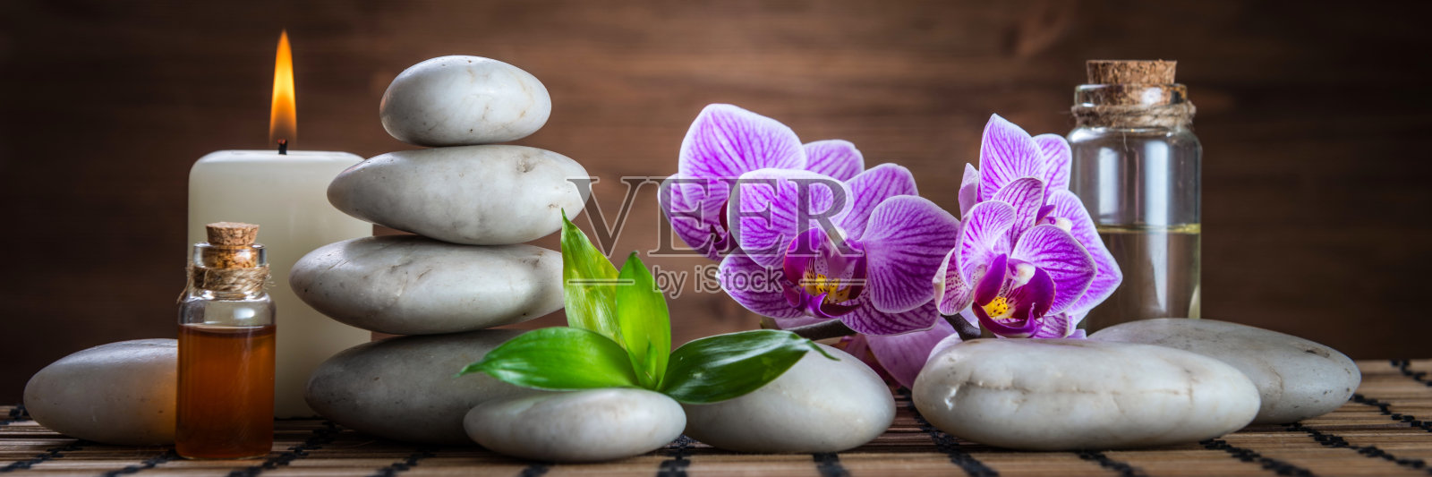 按摩油，白色禅宗平衡石，兰花和竹叶在木桌上照片摄影图片