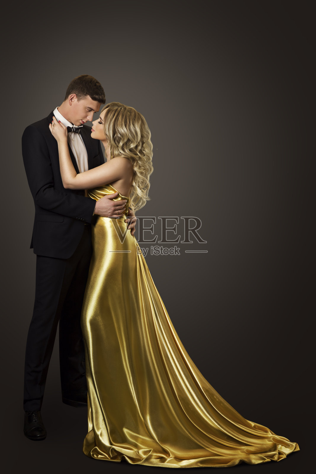 时尚情侣美女肖像，接吻的男人和女人，穿着金色的裙子和黑色的套装照片摄影图片