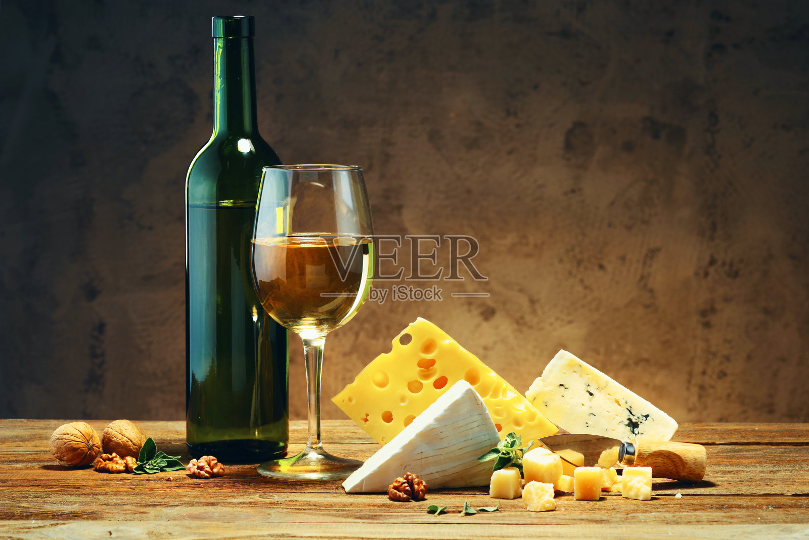 奶酪，一个玻璃杯和一瓶葡萄酒放在一张木桌上。照片摄影图片