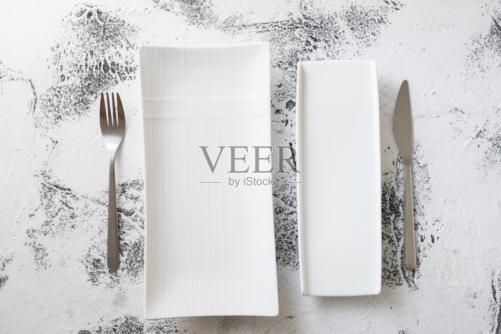 白色的长方形盘子，叉子和刀在白色的木制背景上照片摄影图片