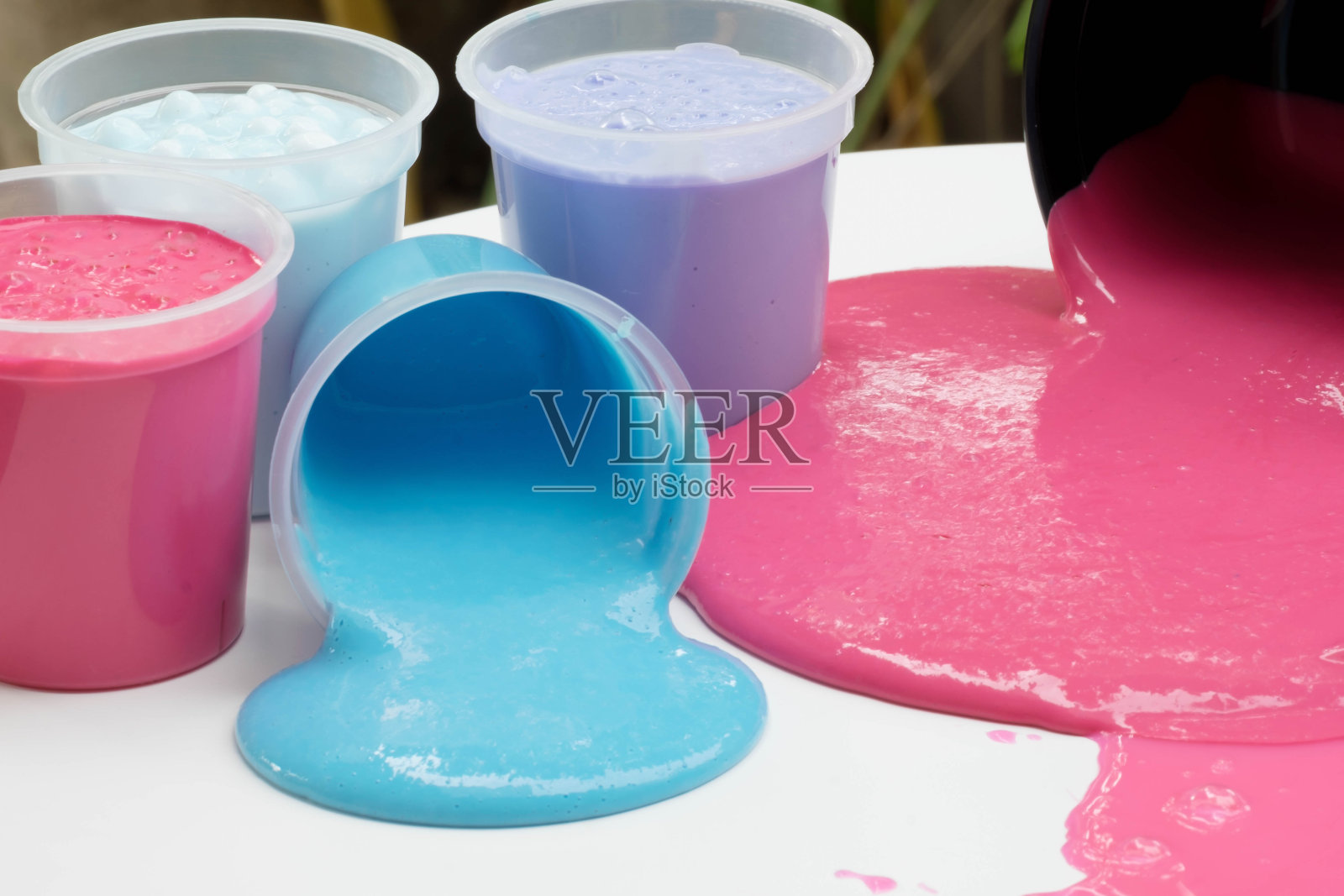 自制玩具瓶被称为黏液，彩色的科学玩具在容器溢出在桌子上，选择性关注黏液。照片摄影图片