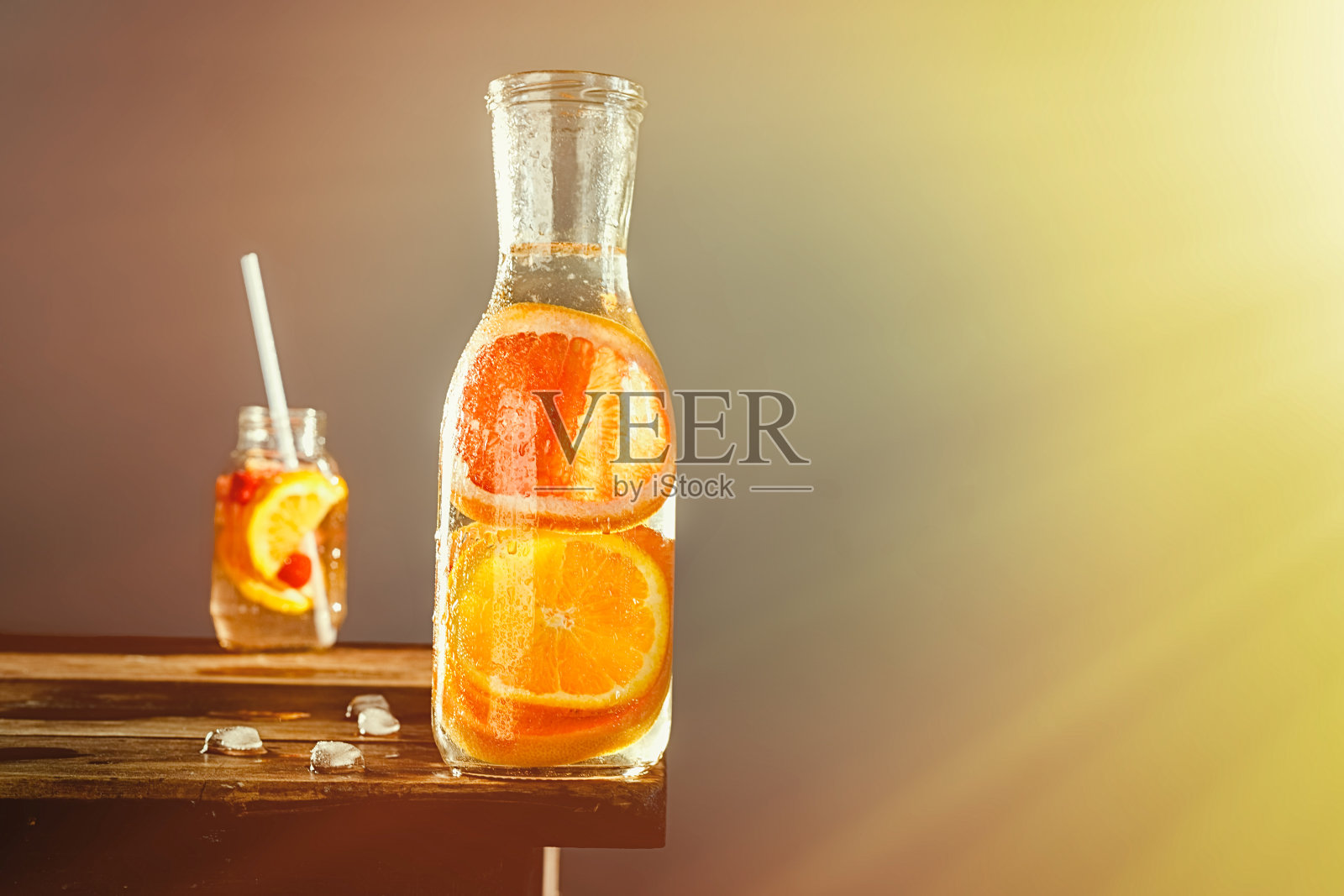 新鲜的橙汁和葡萄柚汁装在一个大的和小的玻璃杯里，放在一张木桌上照片摄影图片