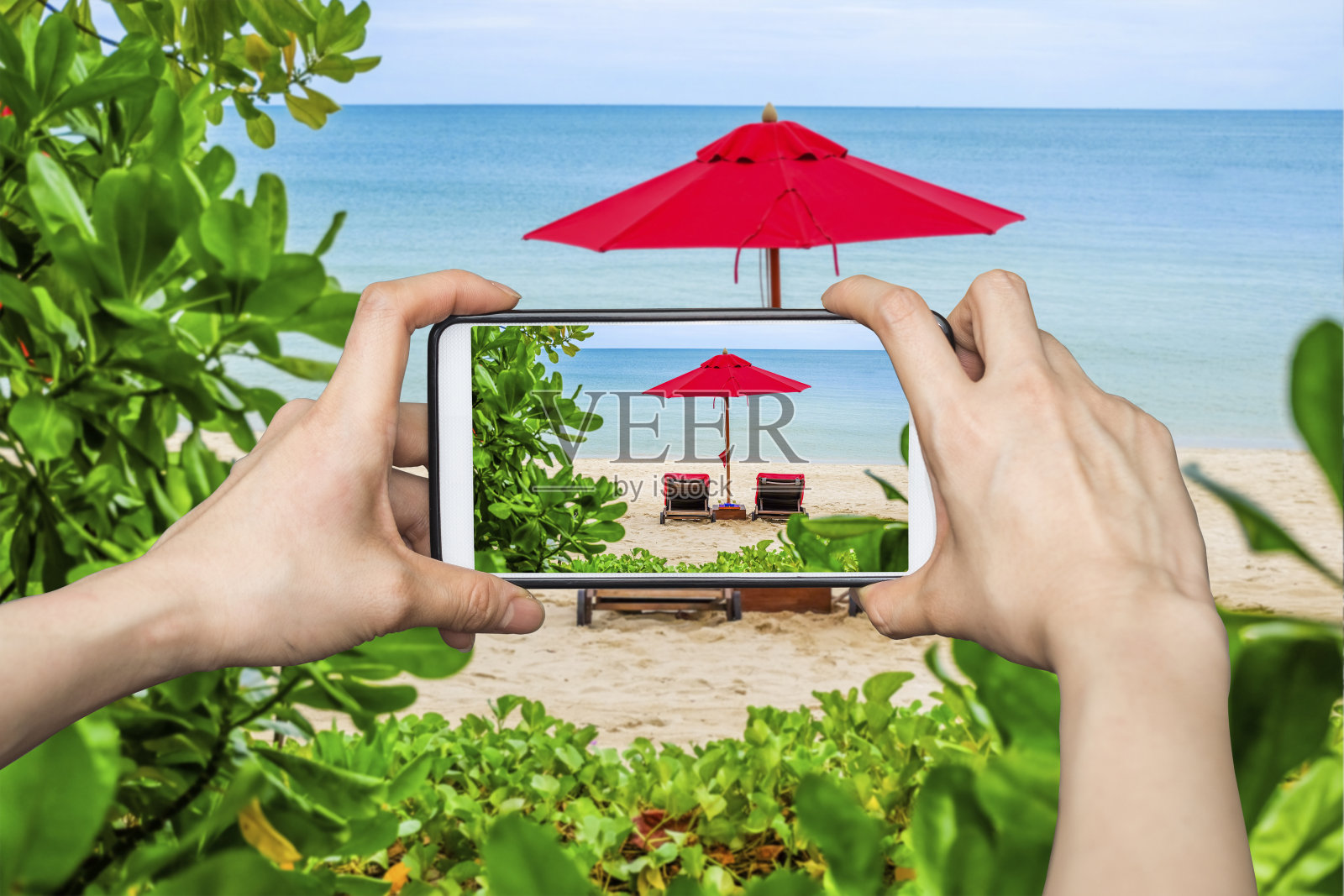 一名正在用手机拍照的女子在海滩上展示红伞照片摄影图片