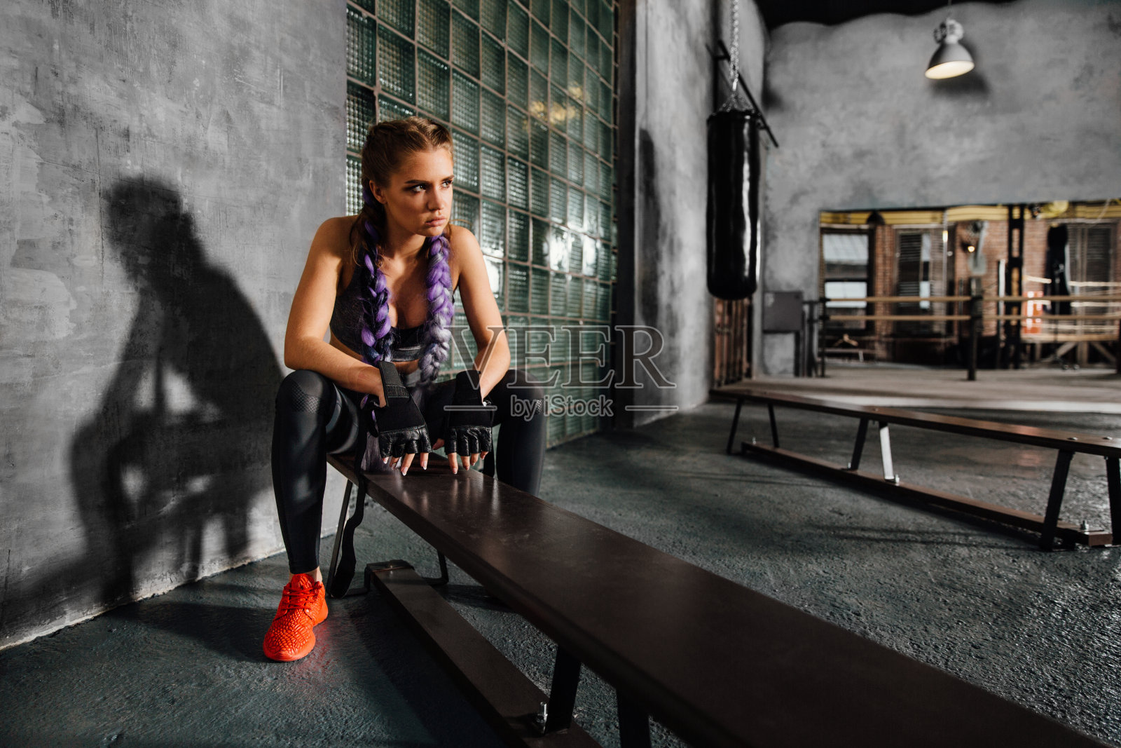 健身女孩放松坐在体育学校的长凳后，一个艰苦的拳击训练照片摄影图片