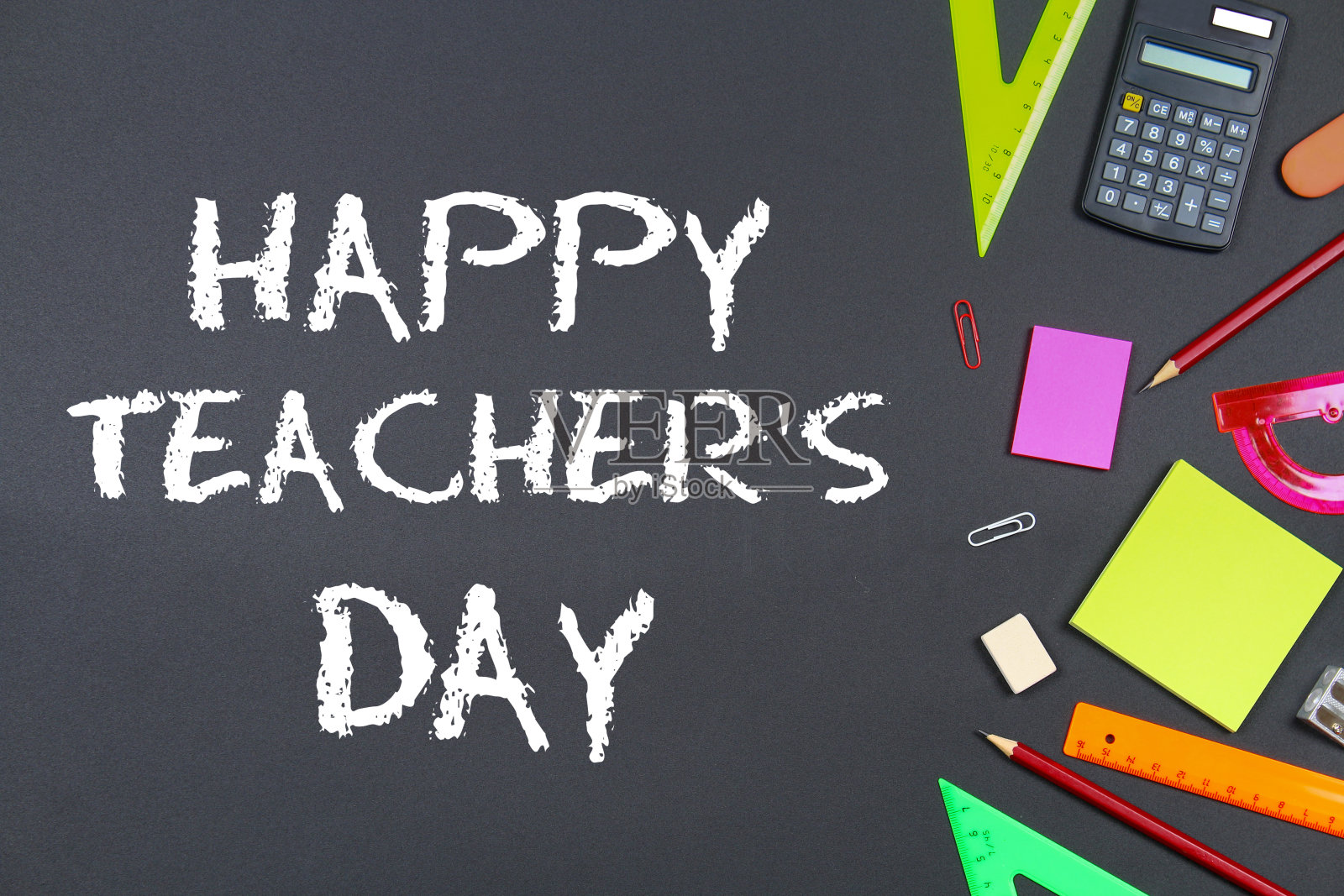 文字粉笔在黑板上:教师节快乐。学校用品，办公室，书籍，苹果。照片摄影图片