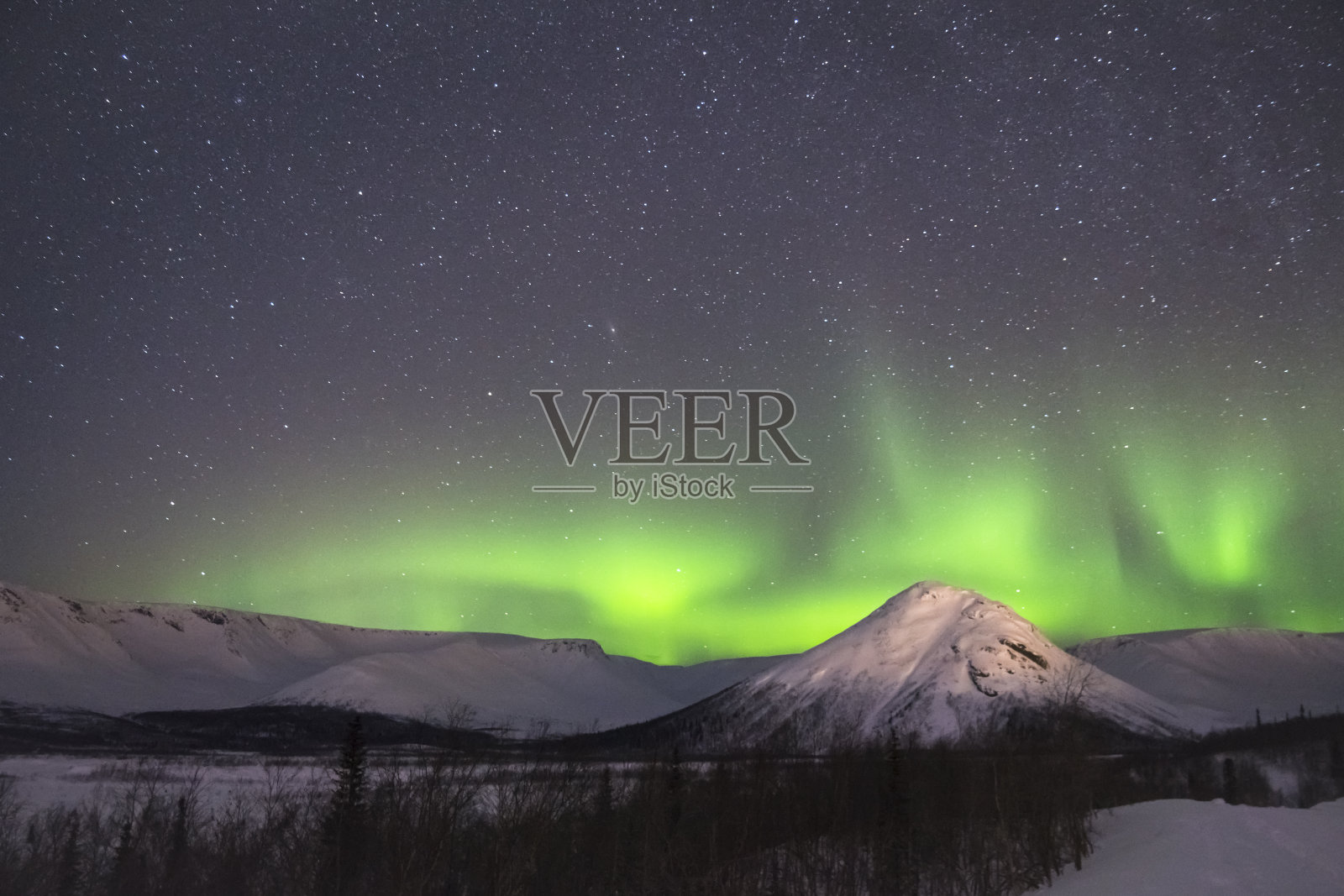夜晚星空和绿色北极光。雪山冬夜照片摄影图片