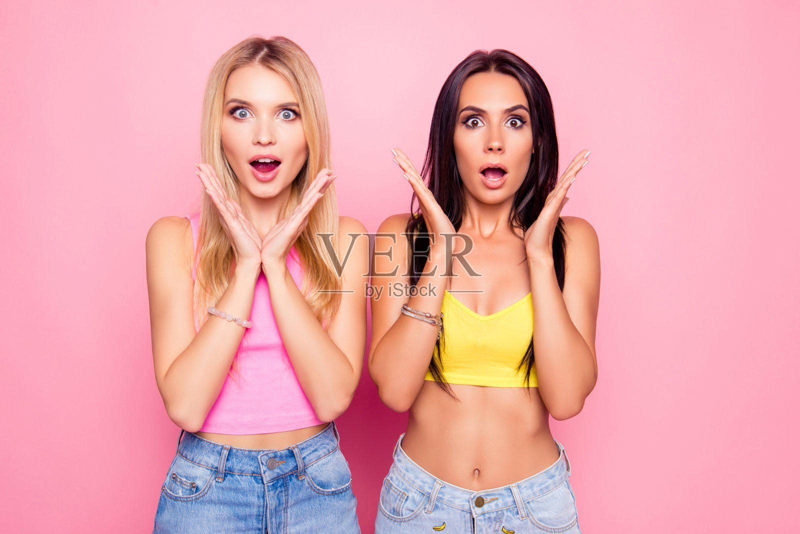 哇!难以置信，你是个骗子!肖像两个迷人的迷人的快乐的美丽惊奇惊奇的女朋友穿着休闲的夏季服装，孤立在明亮的粉红色背景照片摄影图片
