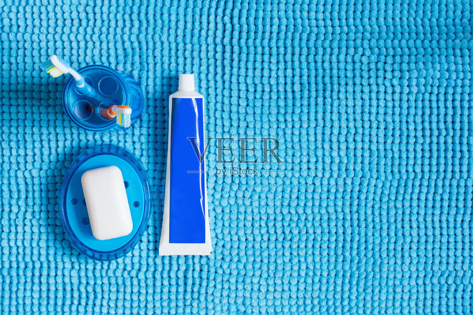 带牙刷的蓝色玻璃，牙膏管和带白色肥皂的肥皂盒。照片摄影图片