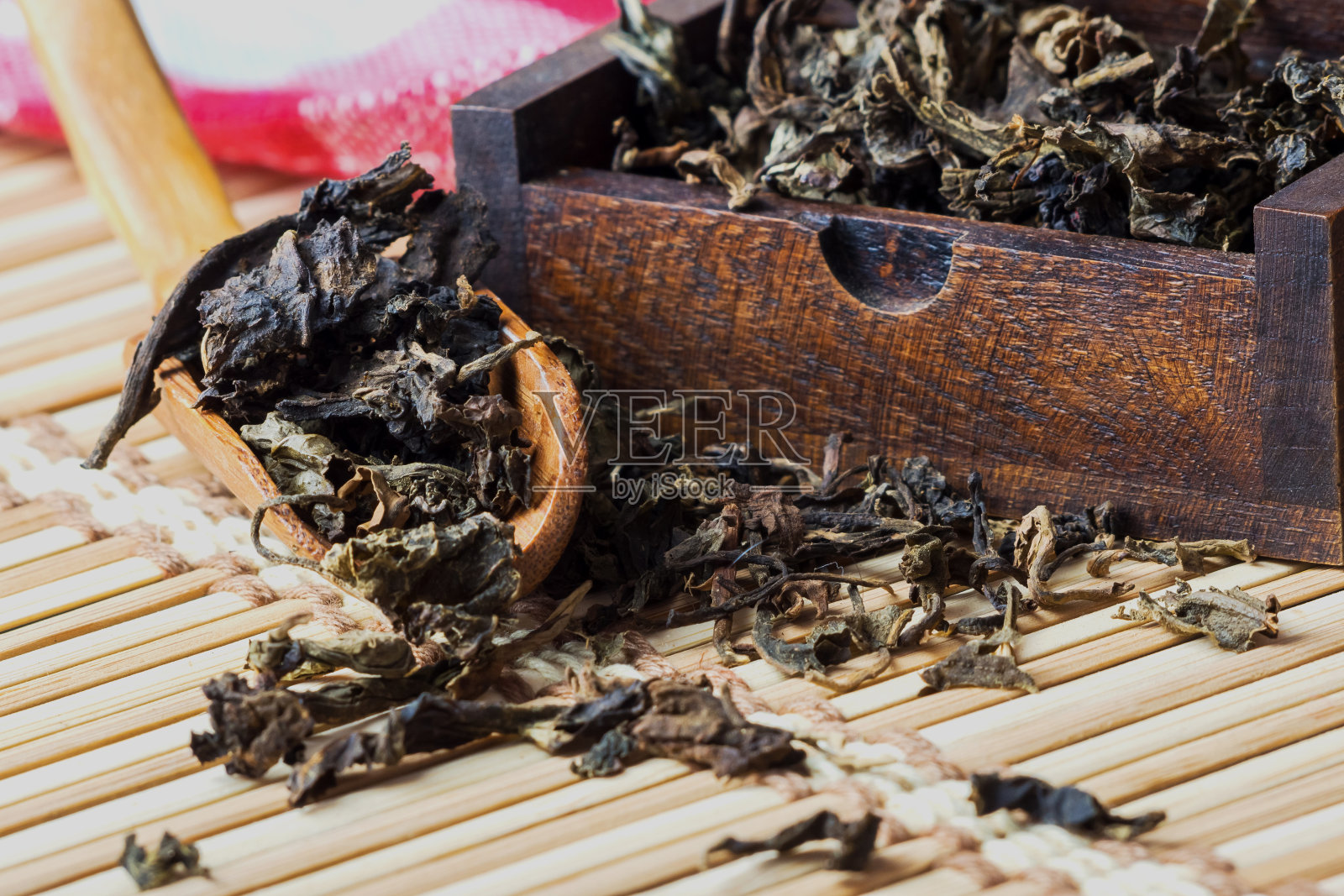 用小木盒装干茶叶，用木茶匙放在竹席上照片摄影图片