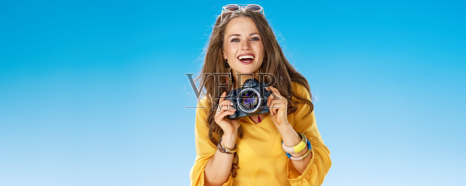 带着数码单反相机在海边微笑的健康女人照片摄影图片