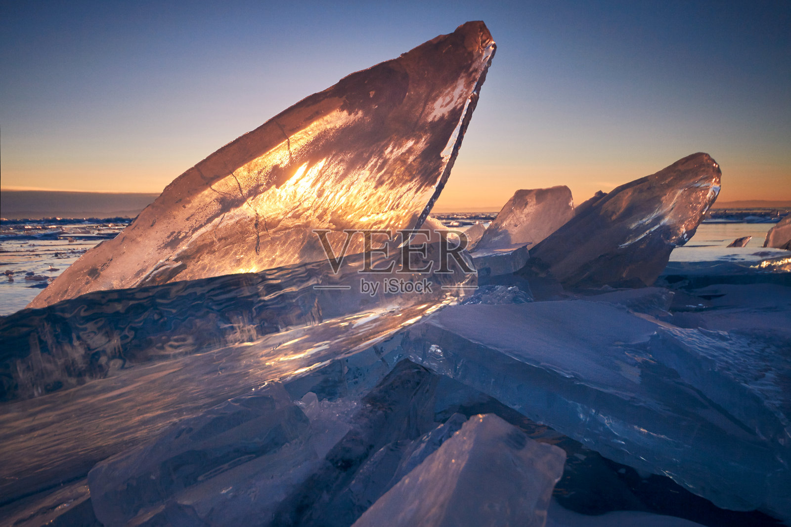 日落时分，贝加尔湖上的一切都被冰雪覆盖着，厚厚的透明的蓝色冰。夕阳下的贝加尔湖。令人惊叹的地方，联合国教科文组织世界遗产照片摄影图片