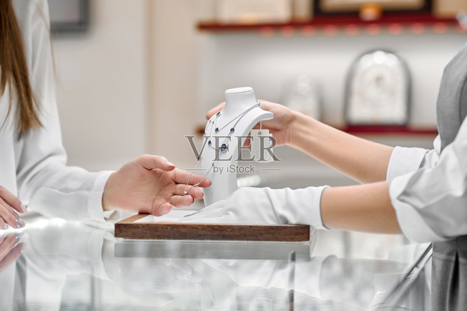 在一家珠宝店，女顾客正在检查珠宝店工作人员赠送的项链。照片摄影图片