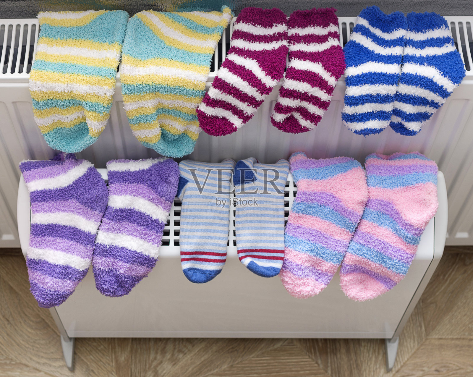 温暖的毛巾袜在加热散热器和电加热散热器在家里干燥。照片摄影图片