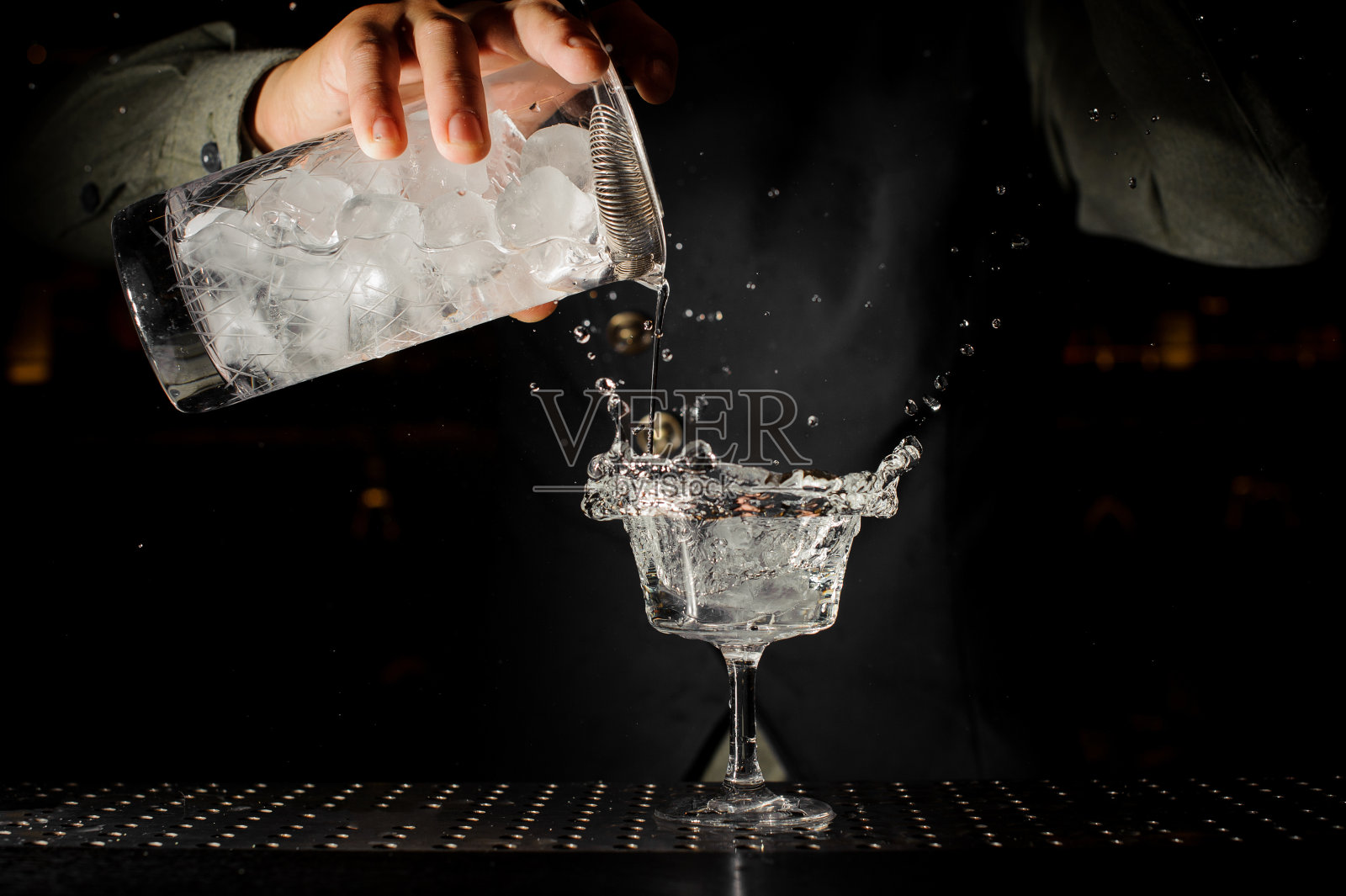 酒保在透明的饮料中加入冰块照片摄影图片