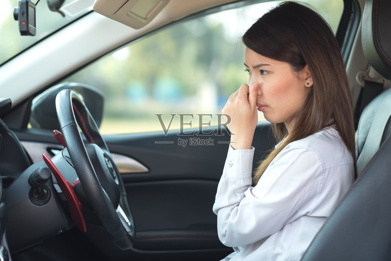 年轻女子捂着鼻子，因为车里有难闻的气味照片摄影图片