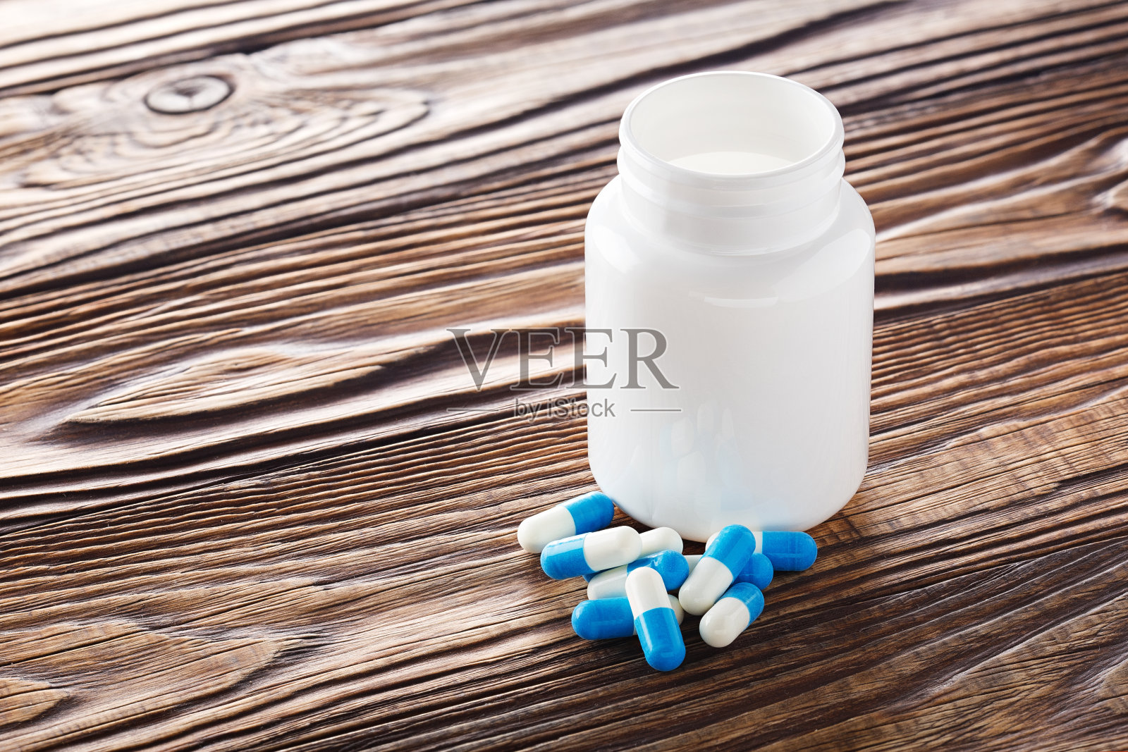 医学蓝色药丸和白色瓶子在木制背景。照片摄影图片