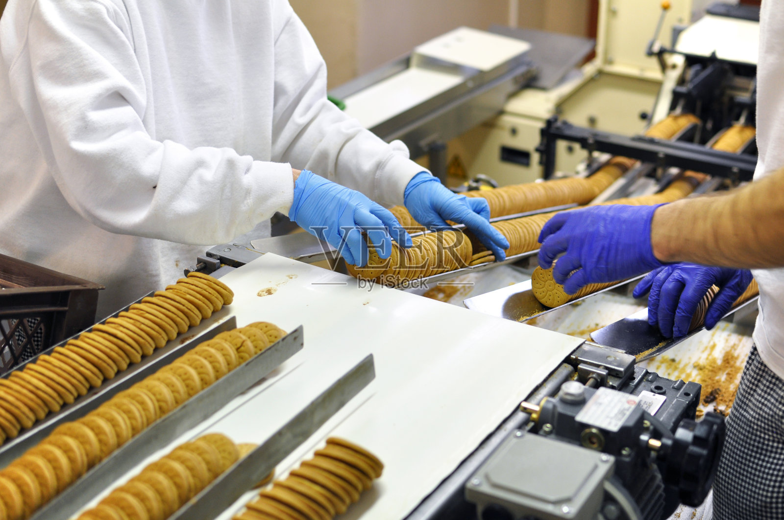 工人们在工厂的传送带上分类饼干，这是食品工业的生产照片摄影图片
