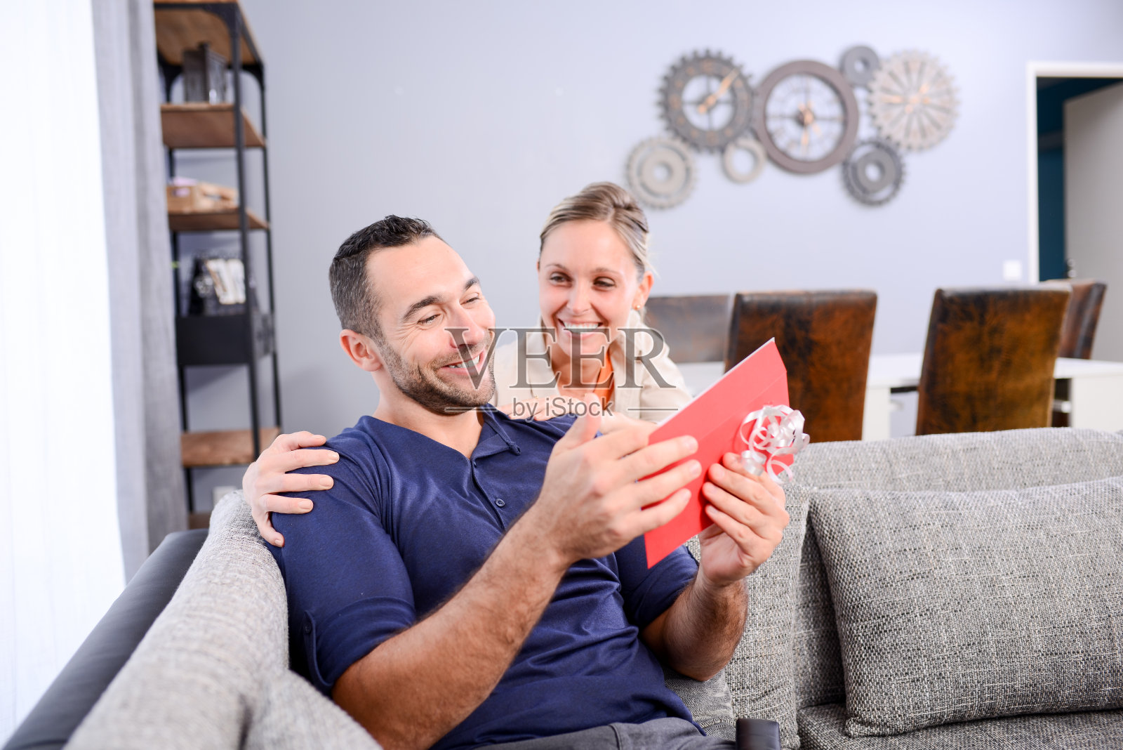 快乐的年轻女子提供惊喜的礼物邀请在信封里给他英俊的男人情人节的男朋友照片摄影图片