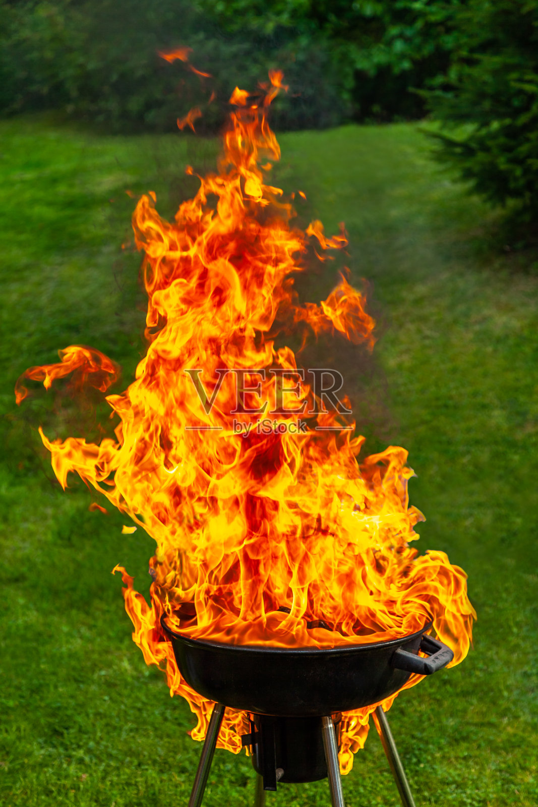 在户外烧烤时，黑色的烤架上闪着一团大火。照片摄影图片