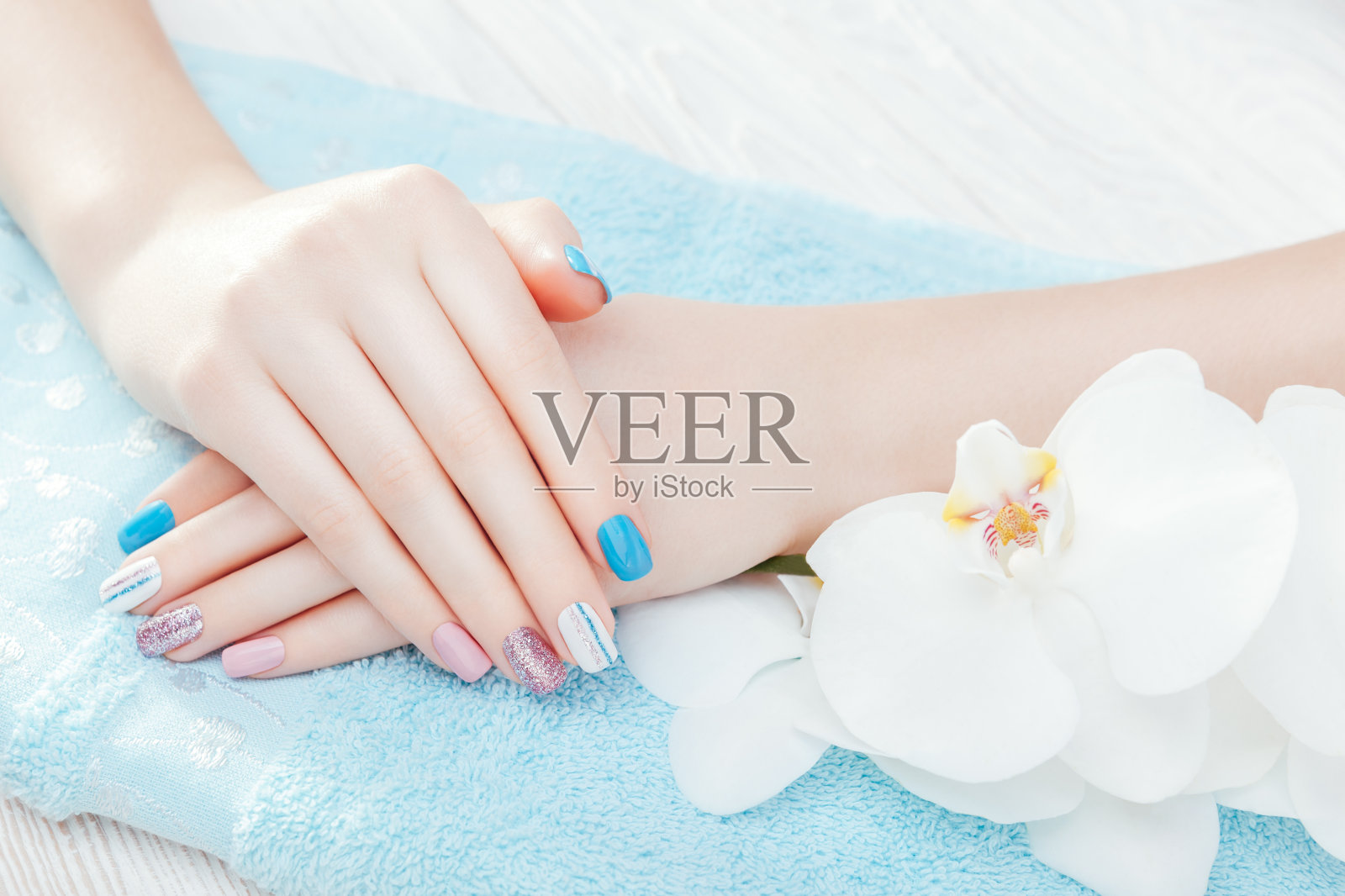 柔和的蓝色，粉红色和白色指甲与兰花。身体护理的概念照片摄影图片