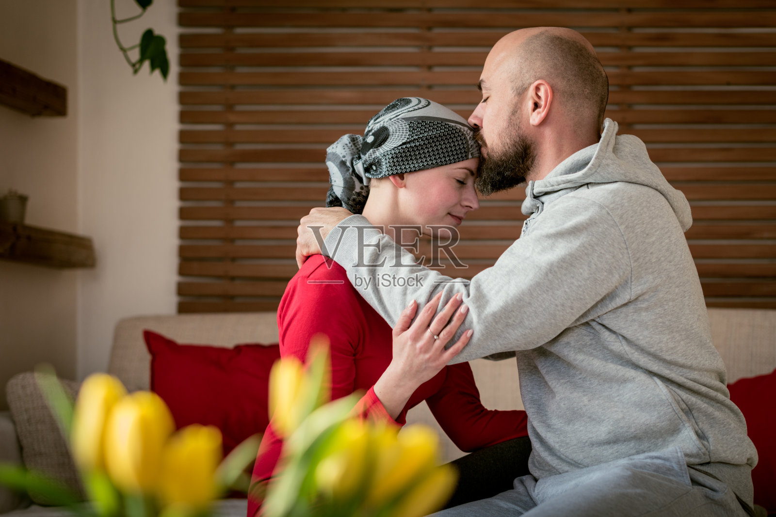支持他的丈夫亲吻他的妻子，癌症患者，在医院治疗后。癌症和家庭支持的概念。照片摄影图片