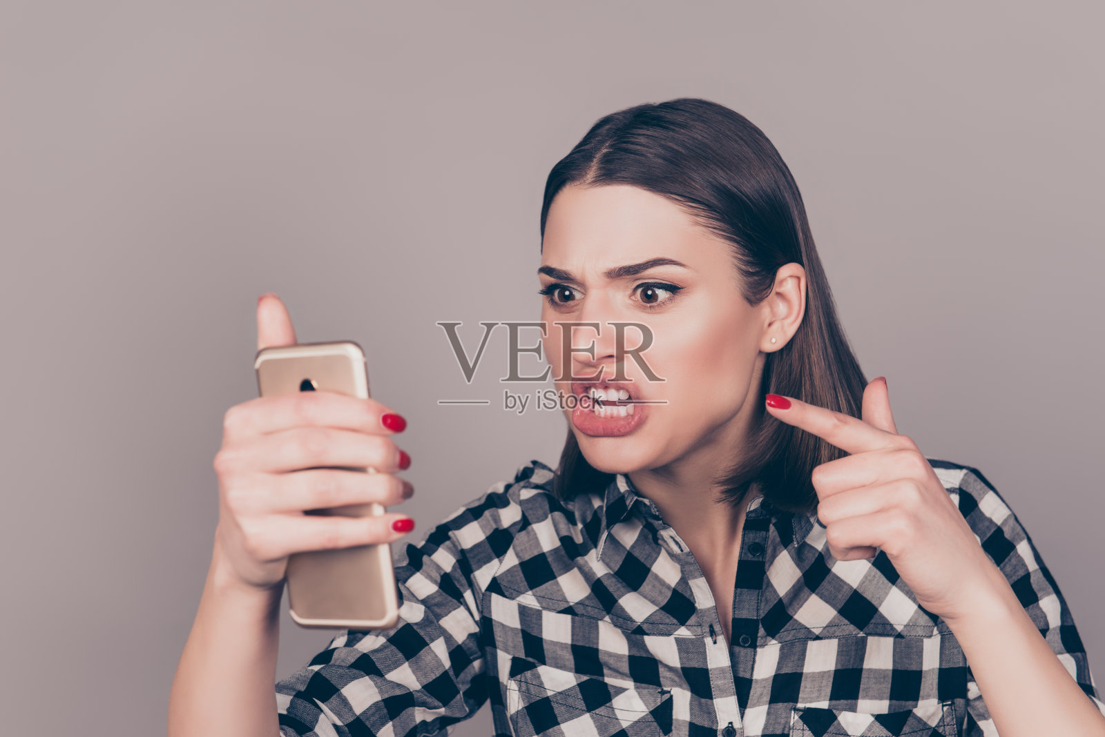年轻愤怒的女人一边和男友聊天一边对着手机大喊大叫照片摄影图片
