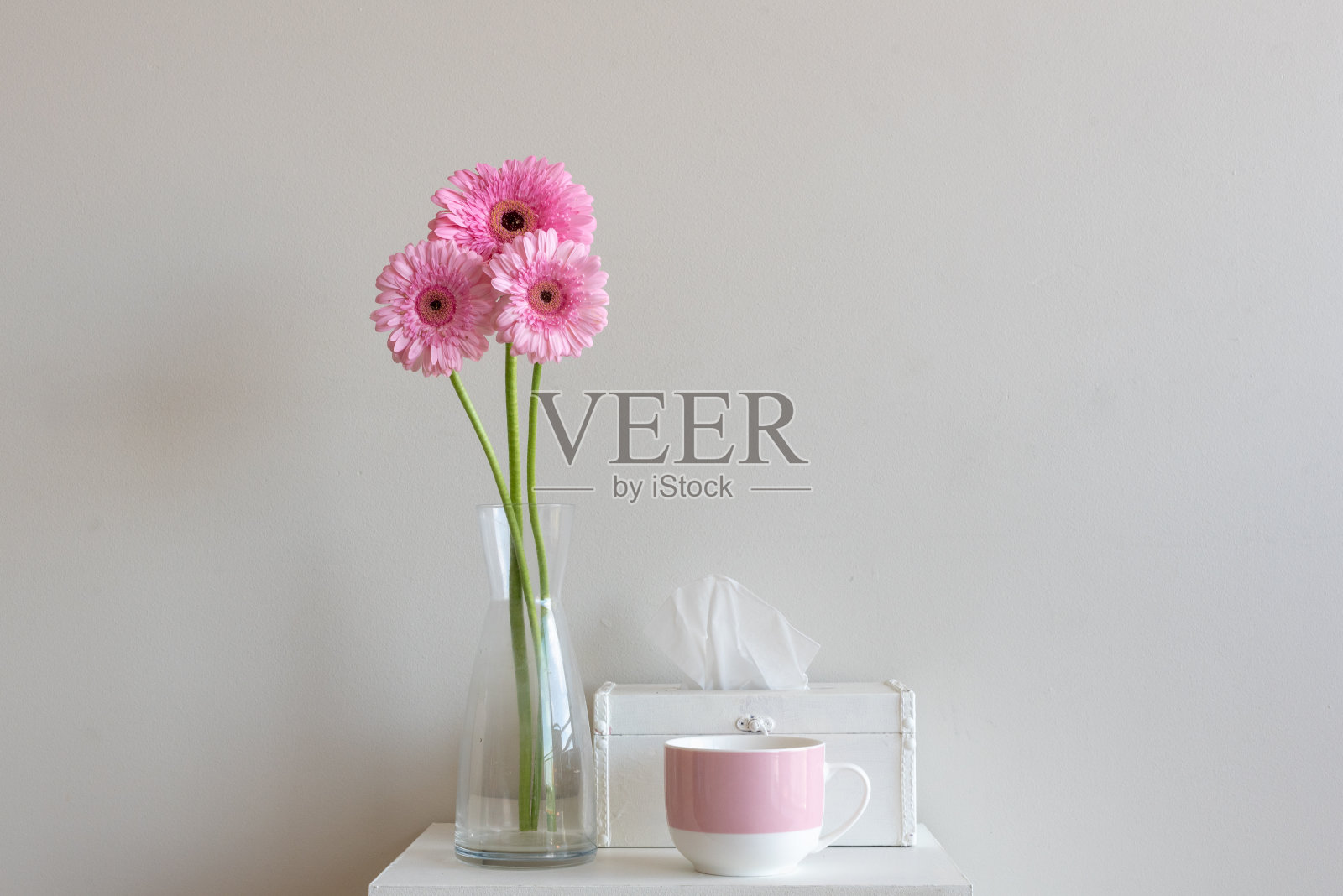 高高的粉色非洲菊，带纸巾盒和粉色马克杯照片摄影图片