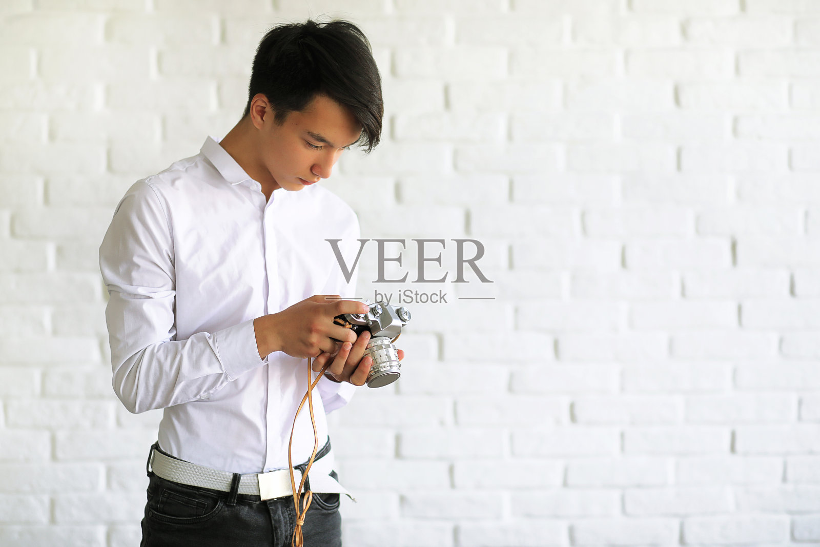一个带着相机的亚洲年轻人照片摄影图片