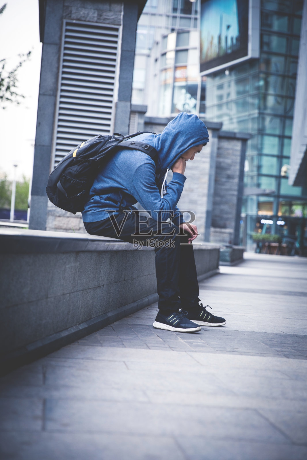 一个悲伤的人坐在城市的街道上照片摄影图片