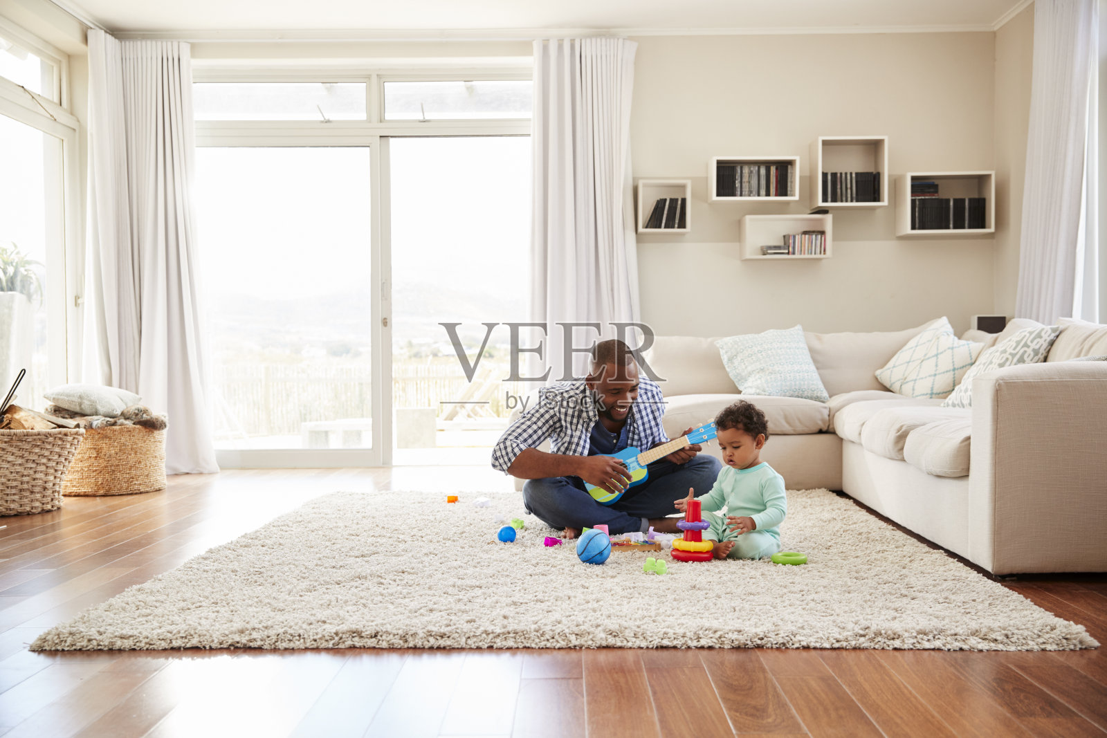 黑人父亲和蹒跚学步的儿子在客厅里玩耍照片摄影图片