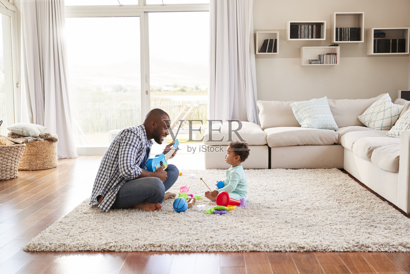 黑人父亲和蹒跚学步的儿子在客厅里玩耍照片摄影图片