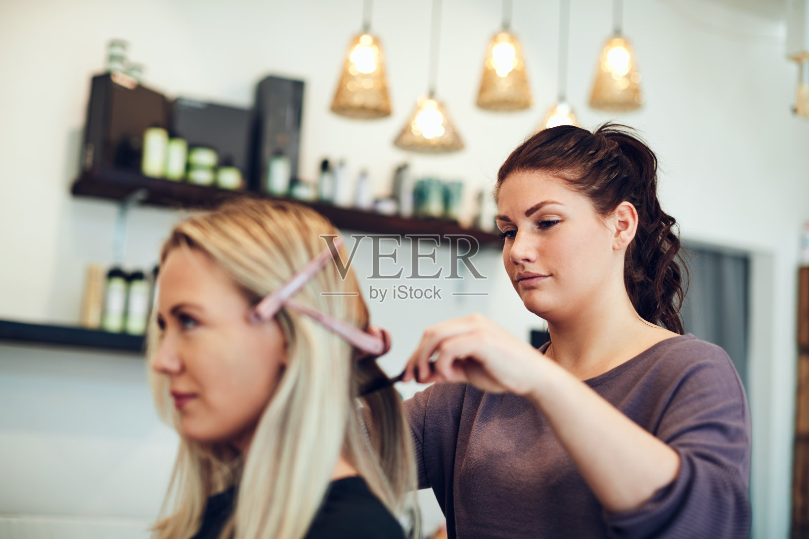 年轻的美发师在她的沙龙里为客户做发型照片摄影图片