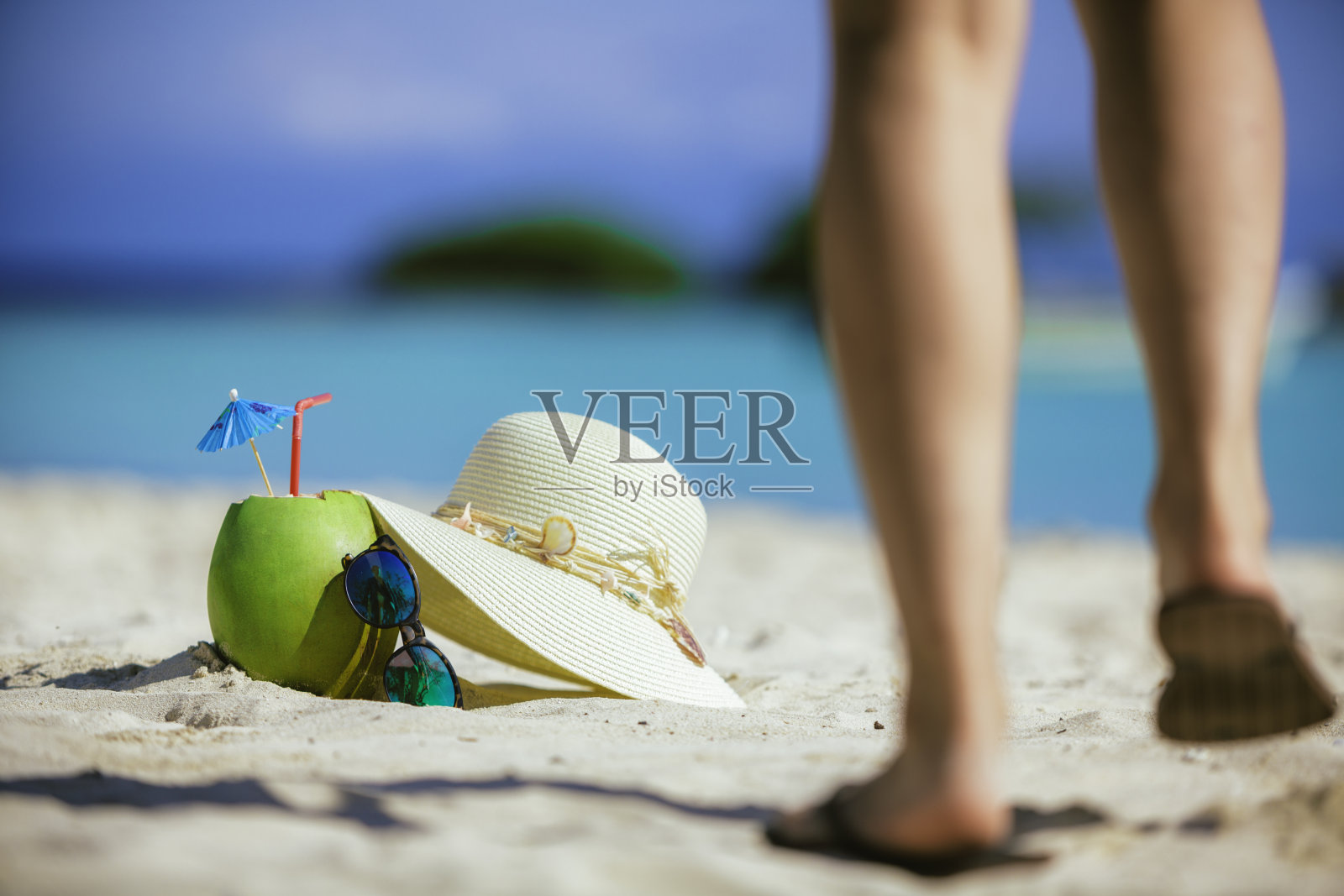 在加勒比海岛屿的绿松石沙滩上，戴着墨镜喝着椰子热带饮料照片摄影图片