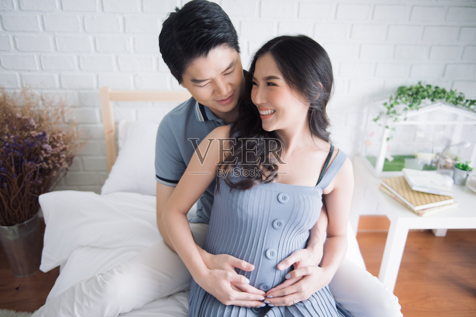 快乐的孕妇和她的丈夫在房间里。照片摄影图片