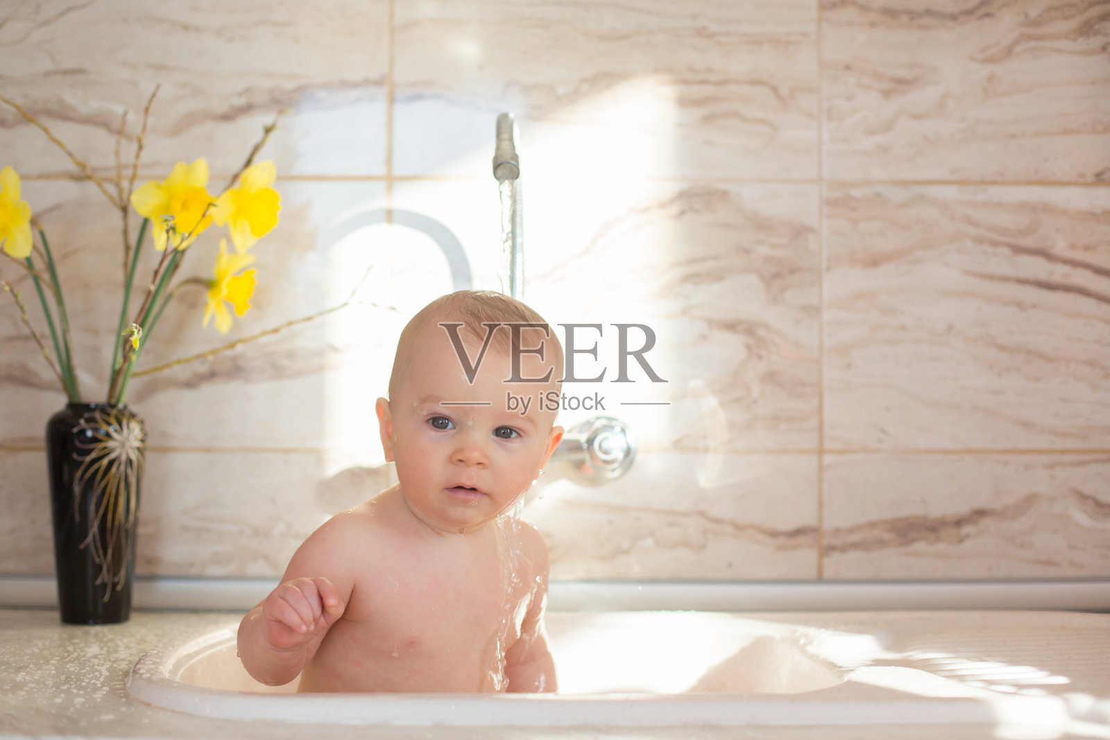 可爱的小男孩，早上在厨房的水槽里洗澡照片摄影图片