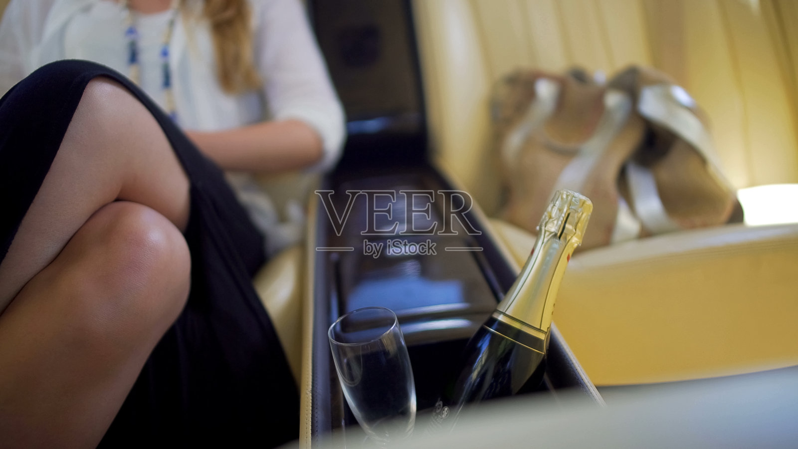 迷人的女人坐在昂贵的车，一瓶香槟和玻璃特写照片摄影图片