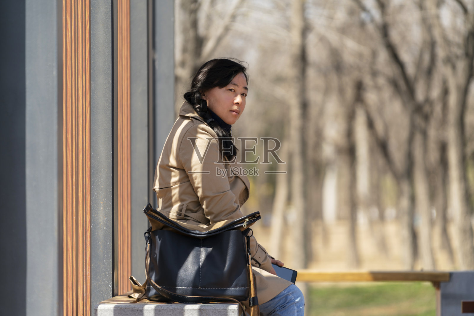 女孩坐在车站的长椅上，等待着照片摄影图片