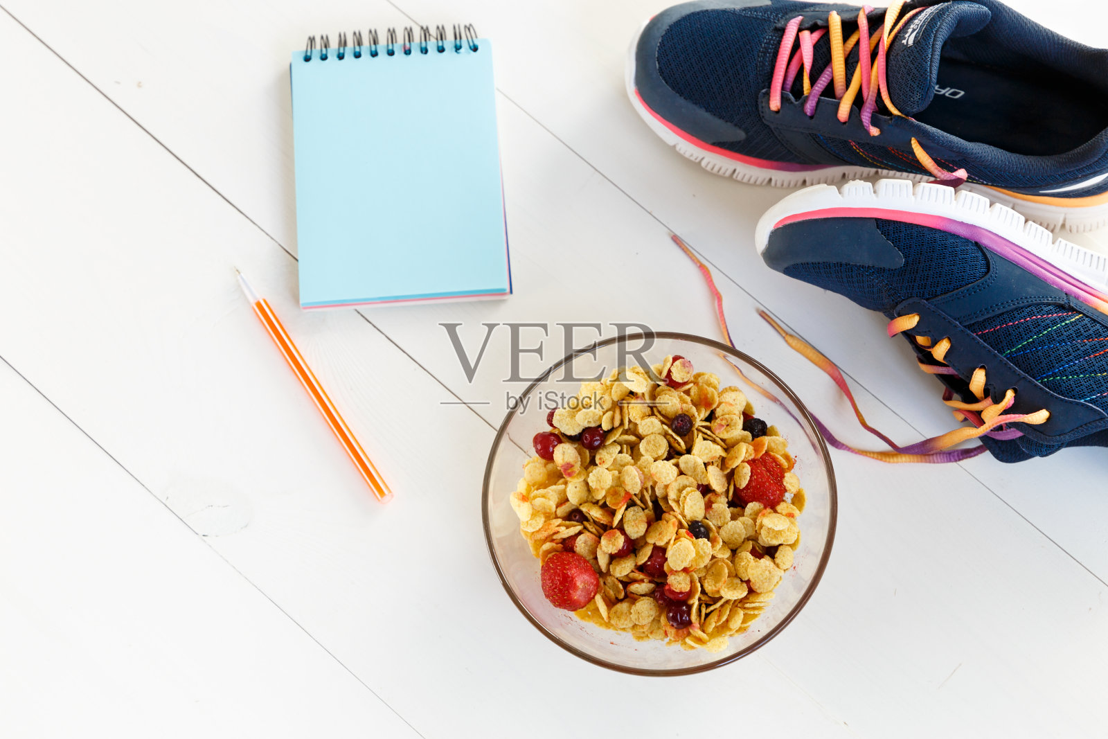 健康的食物和健康的生活方式。在白色的木地板上放着一本书，上面有一张空白的课本，早餐和一双运动鞋。前视图。本空间照片摄影图片
