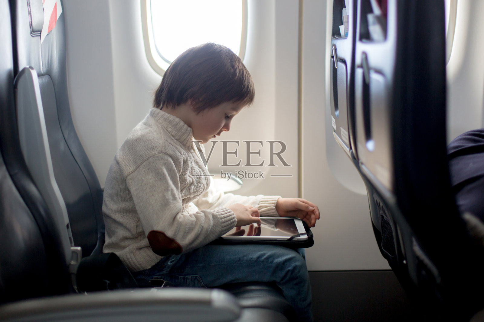 可爱的六岁男孩，在飞机上的桌子上玩照片摄影图片