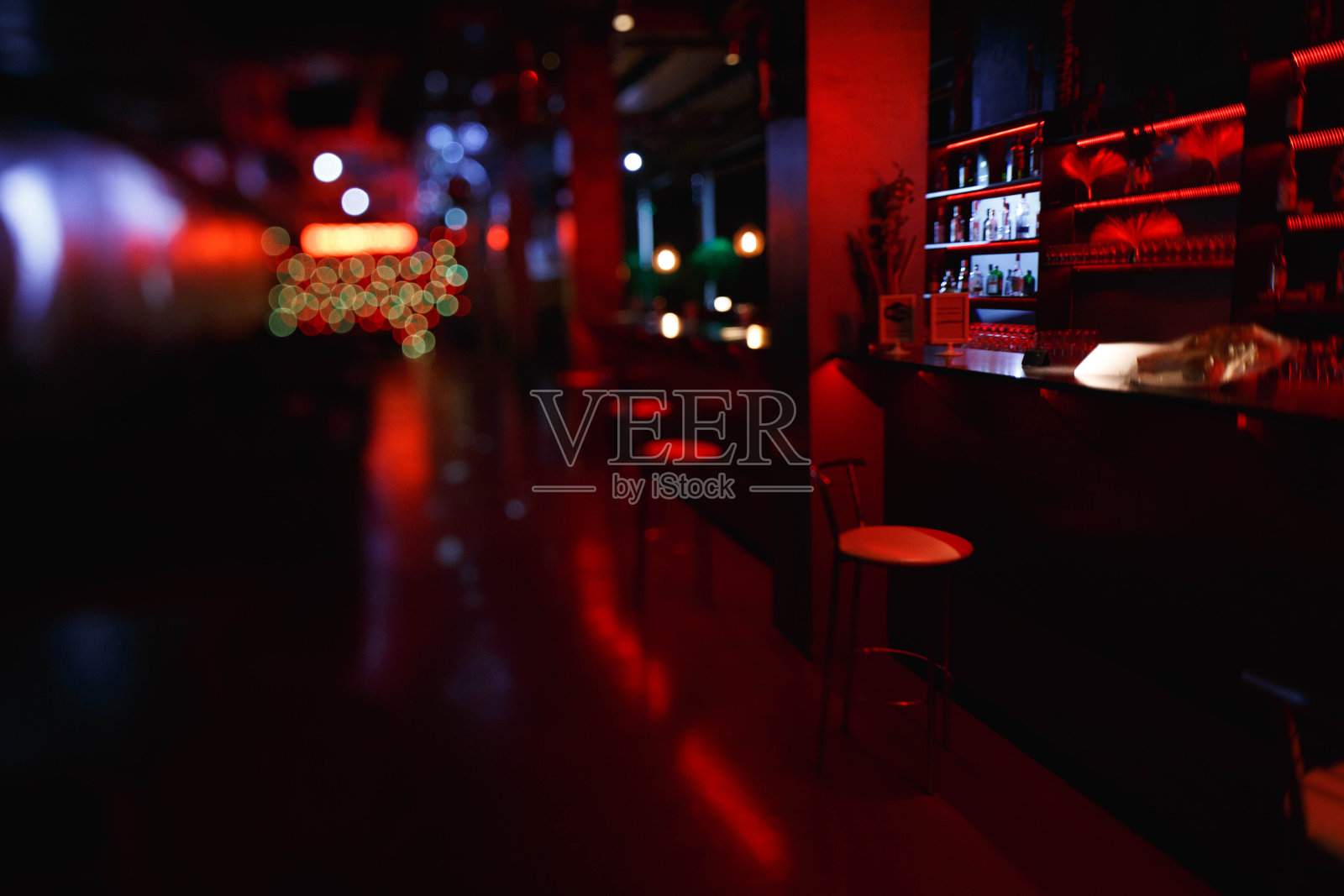 夜间酒吧的室内和家具采用红色照明。酒吧间的凳子在吧台边，镜头倾斜拍摄照片摄影图片