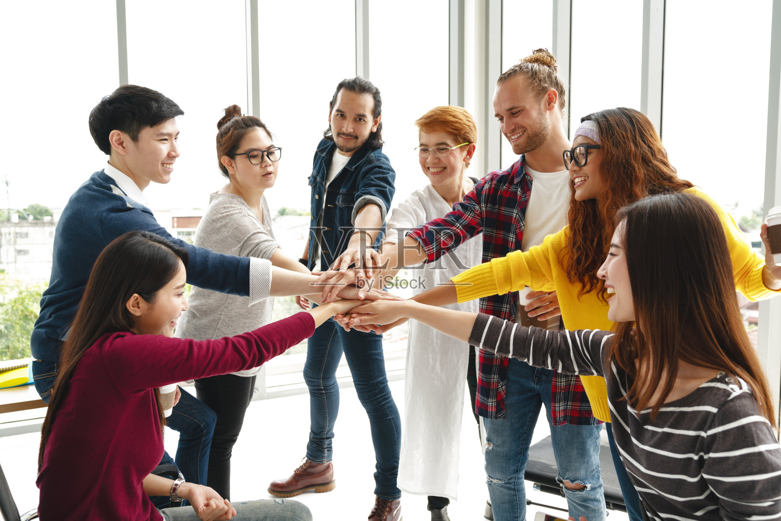 多民族的年轻团队在现代办公室中团结协作，是值得信赖的。不同的团体团结协作或朋友挤在一起的概念。创业团队建设的力量。照片摄影图片