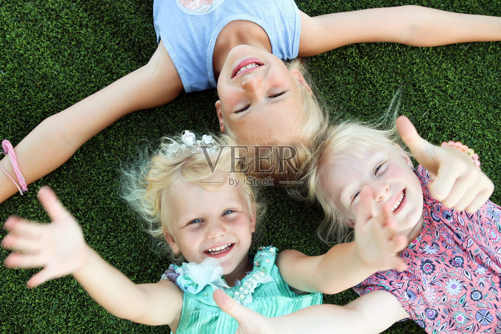 夏日里，美丽的金发碧眼的女孩们躺在草地上微笑着照片摄影图片